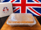 A rectangular tray of baked goods wrapped in clear plastic sits on a wooden board, with a white box labeled Myers of Kenwick and a Union Jack flag in the background.