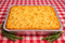 Baked dish in a foil pan on a red and white checkered tablecloth
