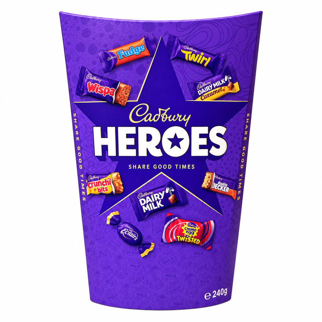 A purple Cadbury Heroes candy tin-shaped cup or container standing on a stone surface with a blurred wooden and indoor background. The front shows the Cadbury Heroes logo and illustrations of assorted chocolates, including Twix, Willy Twister, Dairy Milk, and Cadbury Dairy Butter.