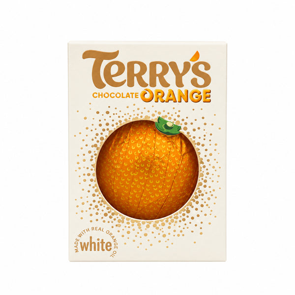 A package of Terry's Chocolate Orange candy stands upright on a wooden counter in a store, with a blurred background showing shelves and a person.