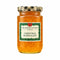 A glass jar of Thursday Cottage Harrogate Christmas Marmalade sits on a rustic wooden table. The jar contains golden orange marmalade and has a green and black checkered lid with a decorative label.