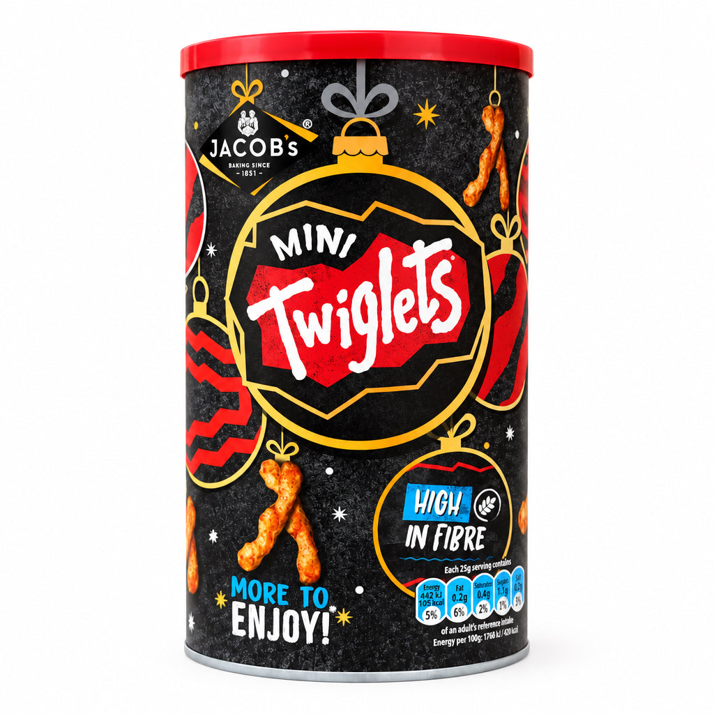 A canister of Jacobs Mini Twiglets high in fibre crisps, featuring a festive black label with red and gold holiday ornament graphics, set on a stone countertop with a blurred wooden background.